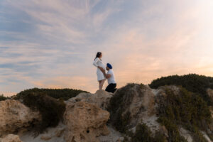 Pregnant woman standing by mossy rocks, Trigg Beach
