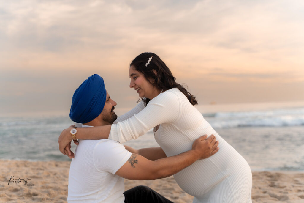 Pregnant woman walking on Trigg Beach at sunset
